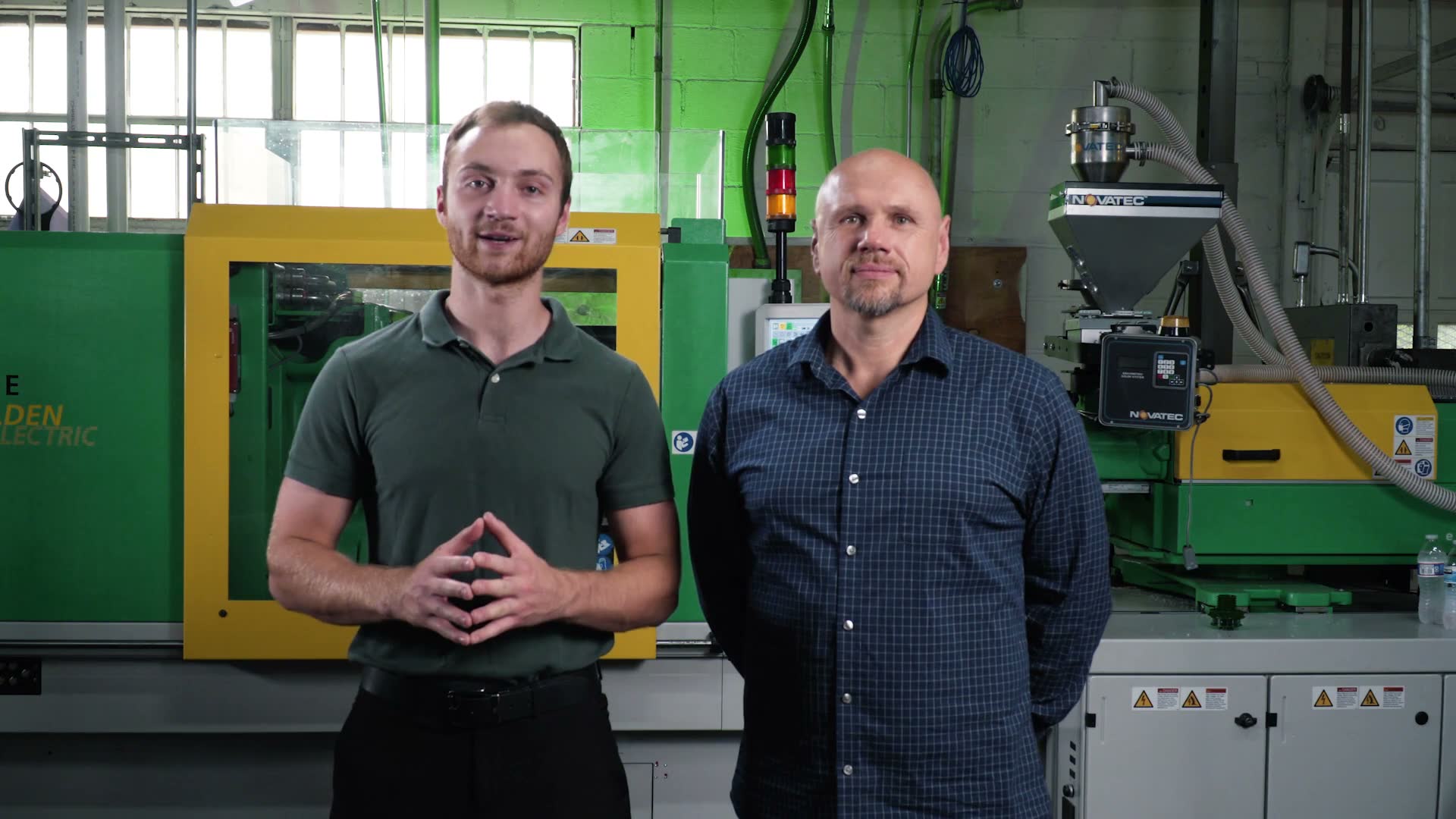 Simon and Christopher Miedza in front of an injection molding press at PharoPLAST in Cleveland, Ohio